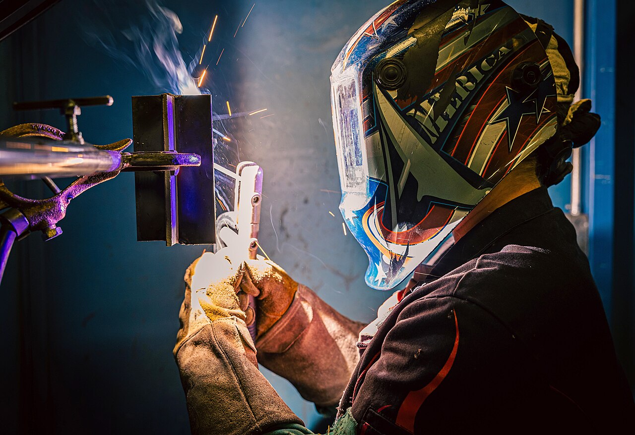 Welder joining steel sections with an arc and sparks